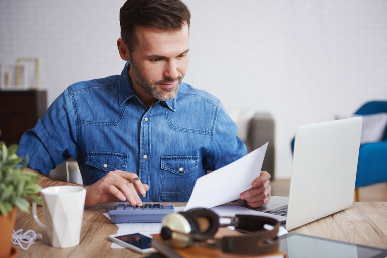 Homme travaillant à l'ordinateur avec une calculatrice.